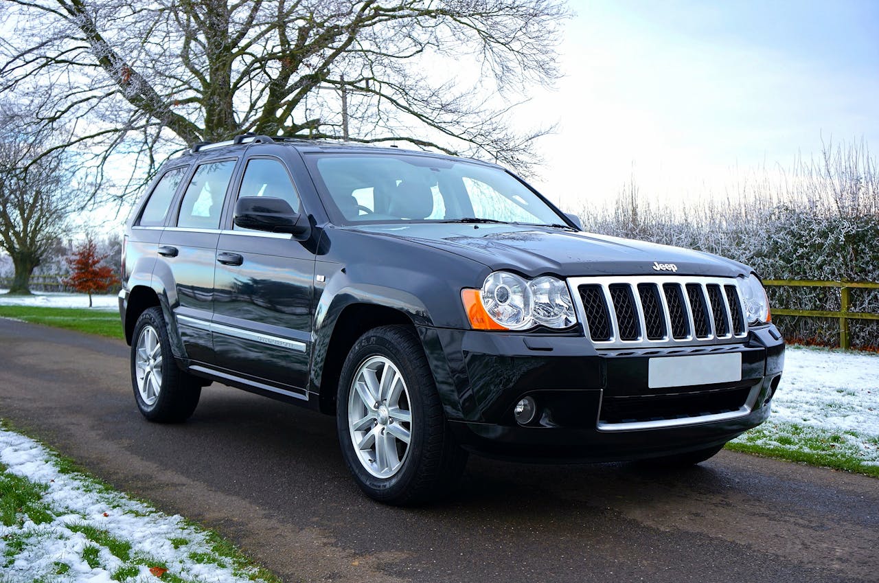 A shiny black SUV parked on a snowy road with trees in the background, showcasing winter scenery.